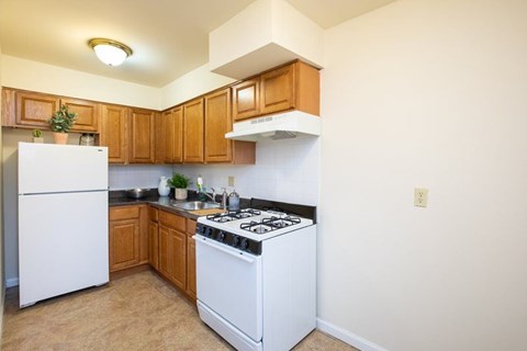 A kitchen with white appliances and wooden cabinets.
