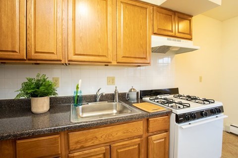 A kitchen with a white stove and wooden cabinets.