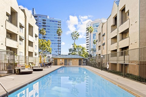 A pool surrounded by buildings and palm trees.at Costa Verde Village Apartments, San Diego, CA