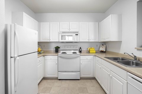 A white kitchen with a refrigerator, oven, and microwave.at Costa Verde Village Apartments, San Diego California