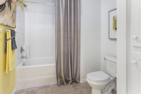 A bathroom with a white toilet and a shower curtain.at Costa Verde Village Apartments, San Diego, CA