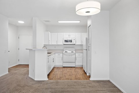 A white kitchen with a brown carpet.at Costa Verde Village Apartments, San Diego, CA 92122