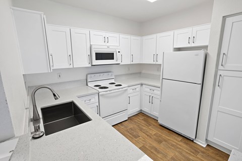 A kitchen with white cabinets and appliances.at Costa Verde Village Apartments, California