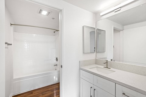 A white bathroom with a sink, mirror, and shower.at Costa Verde Village Apartments, San Diego, CA