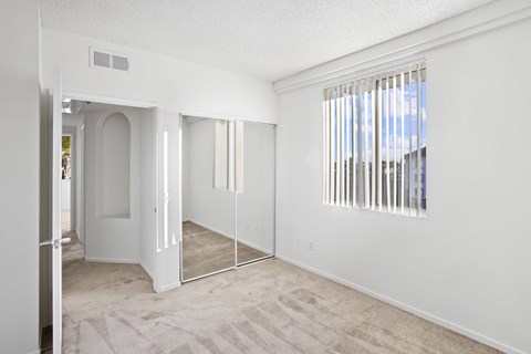 A room with a carpeted floor and a window with blinds.at Costa Verde Village Apartments, San Diego California
