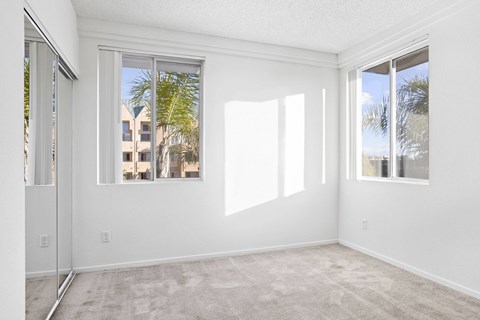 A room with a carpeted floor and a large window.at Costa Verde Village Apartments, San Diego