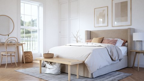 A bedroom with a large bed, a desk with a chair, and a nightstand.