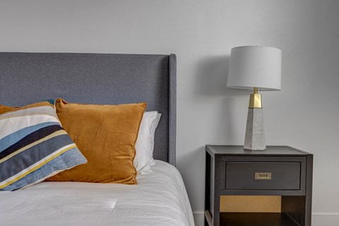 a bedroom with a bed and a nightstand with a lamp on it
