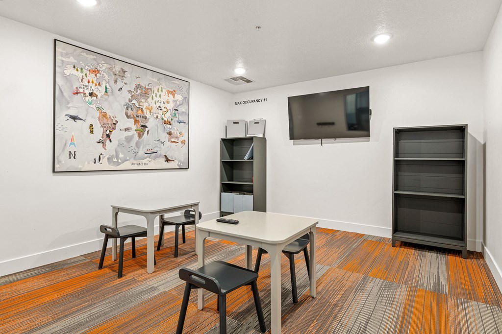 a room with a table and chairs and a television on the wall