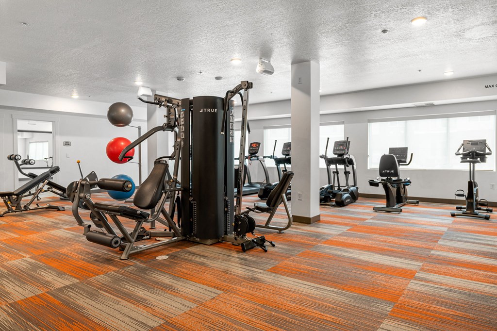 a large fitness room with cardio equipment and weights