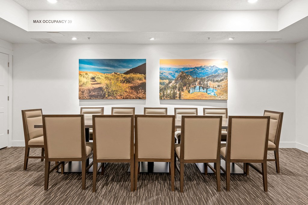 a table with chairs in a room with two paintings on the wall