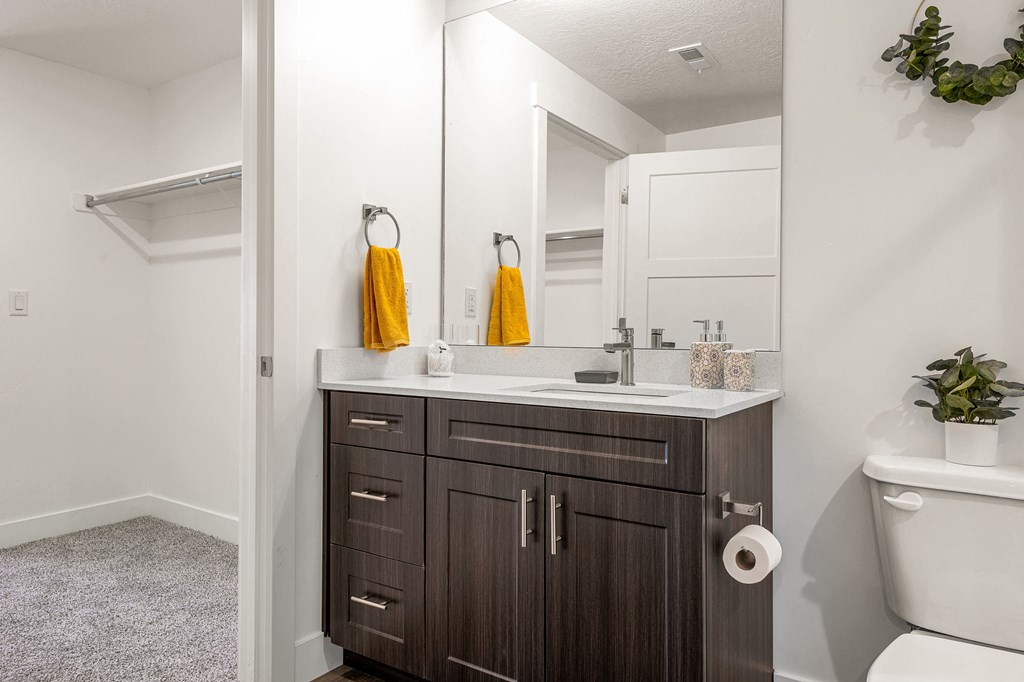 a bathroom with white walls and a dark wood vanity with a white countertop