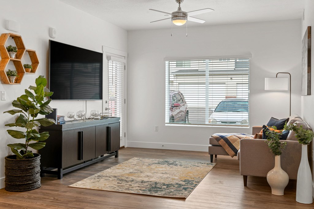 a living area with a ceiling fan and a large window