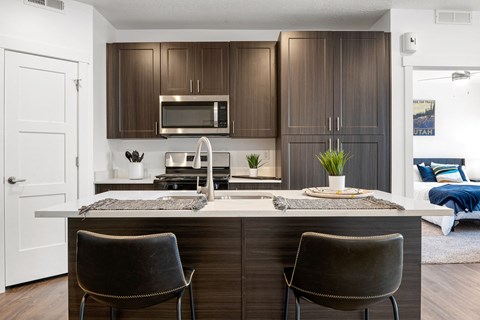 a kitchen with brown cabinets and a counter with two chairs