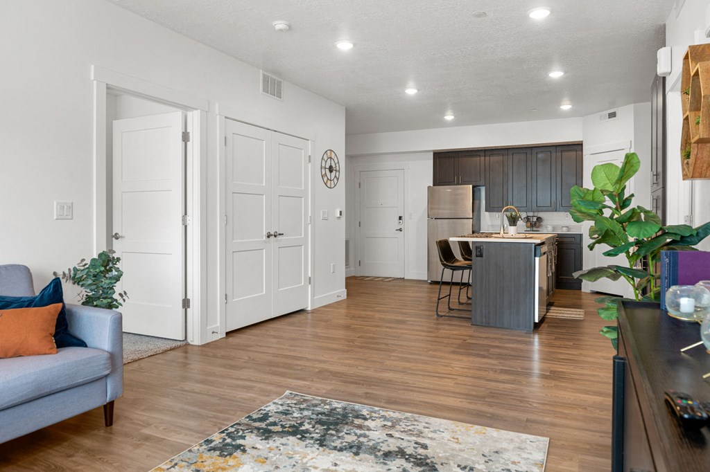 a living room and kitchen area with white walls and hardwood flooring