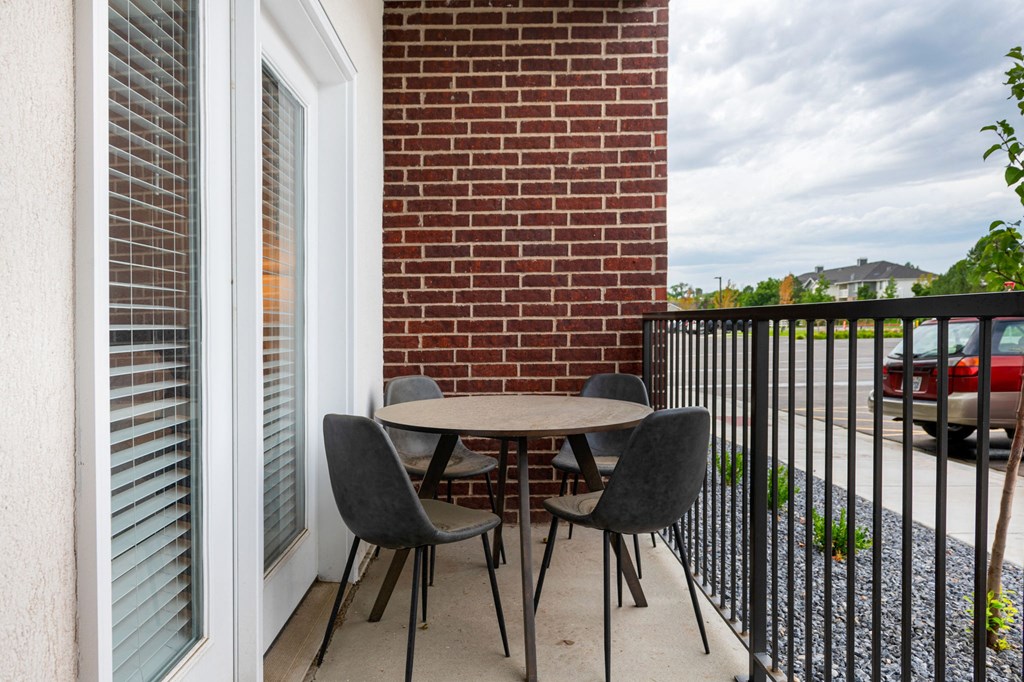 a patio with a table and chairs in front of a brick wall