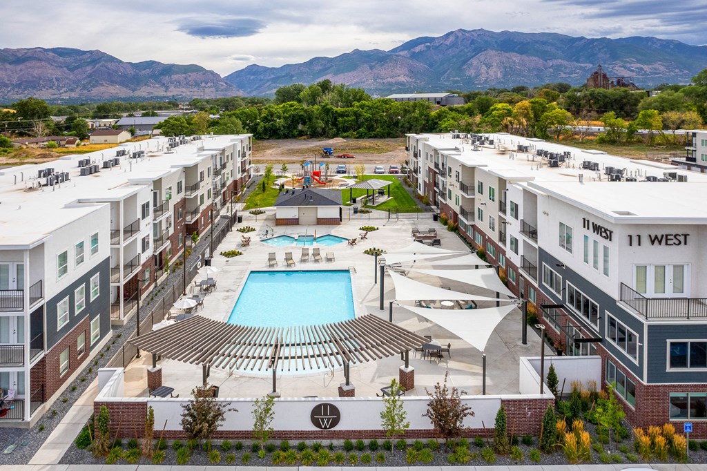 an aerial view of an apartment complex with a pool and mountains in the background