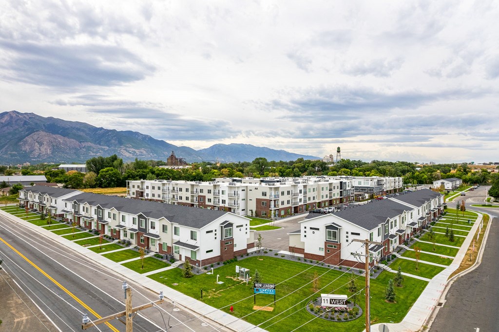 a row of apartment buildings with a street in the foreground and mountains in the background
