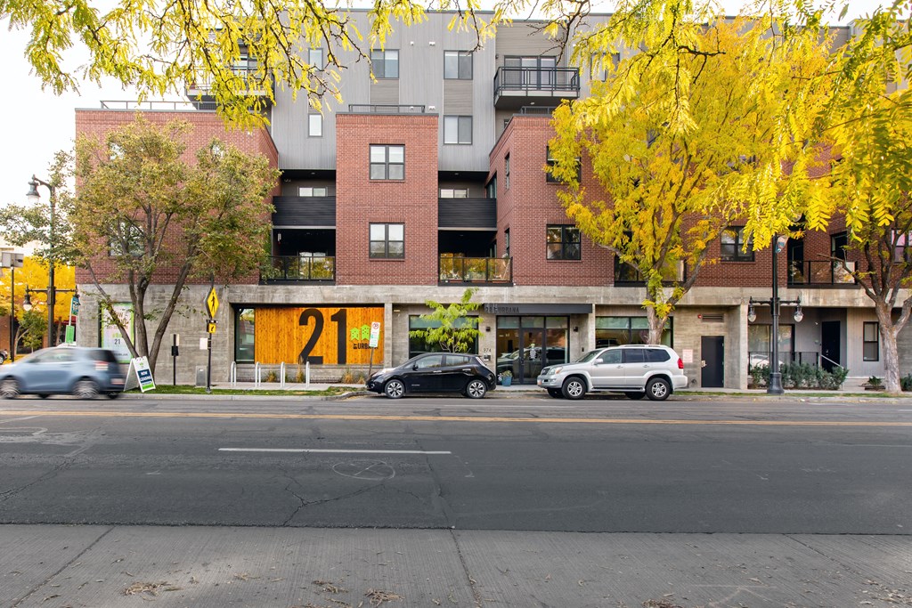 a city street with cars parked in front of an apartment building
