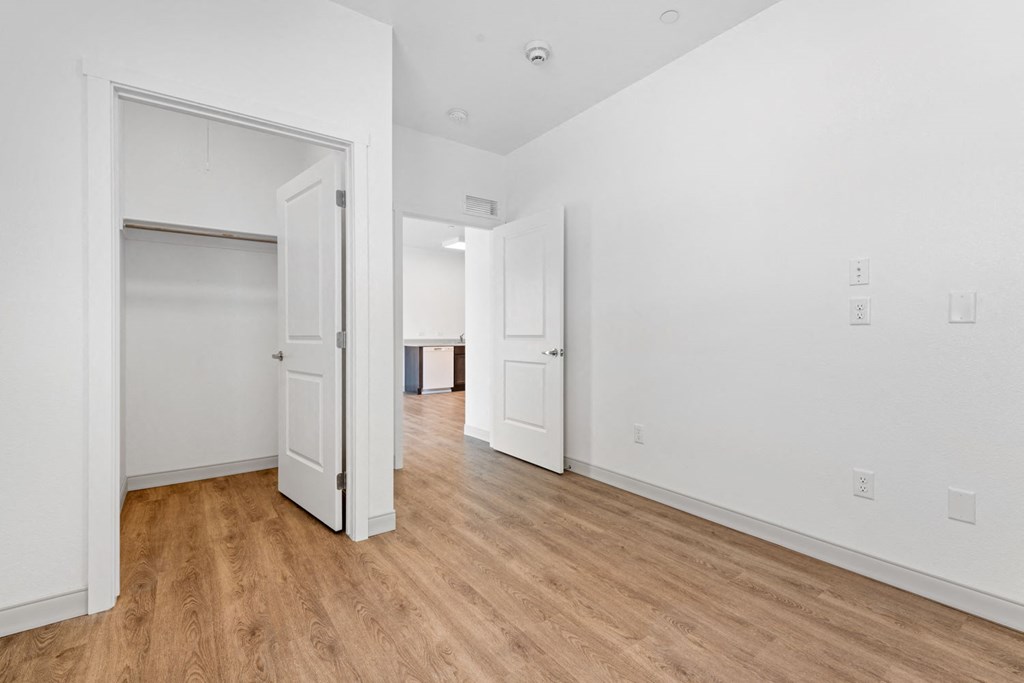 a bedroom with hardwood floors and white walls