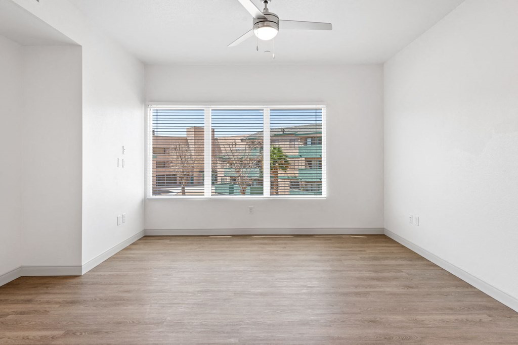 a bedroom with a large window and hardwood floors