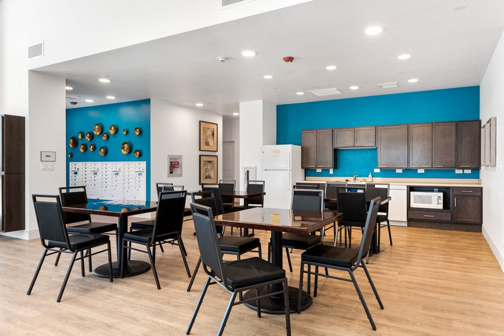 a room with a table and chairs and a kitchen in the background