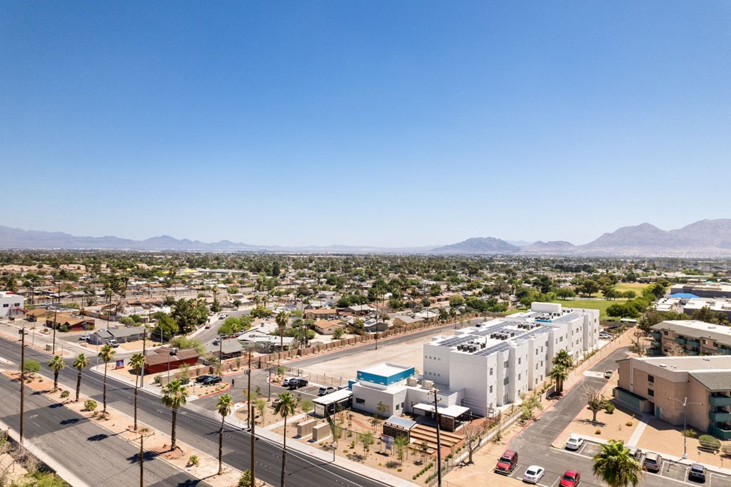 an aerial view of a city with palm trees and mountains in the background