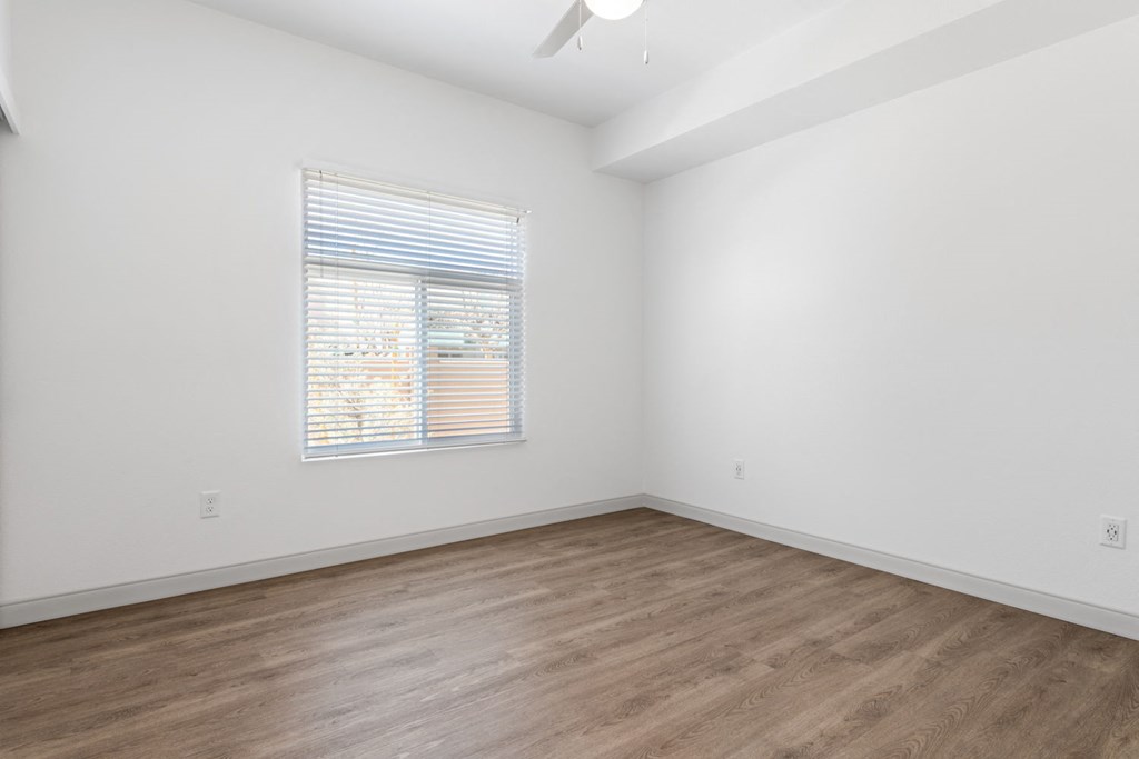 a bedroom with white walls and hardwood floors