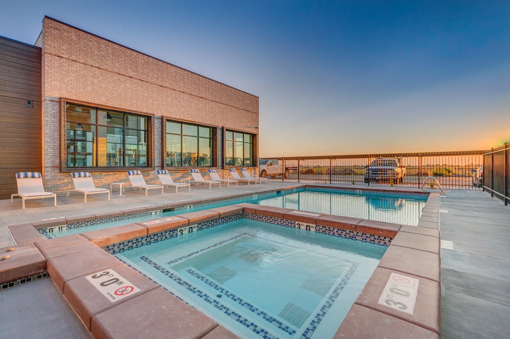 A pool with a red brick building behind it.