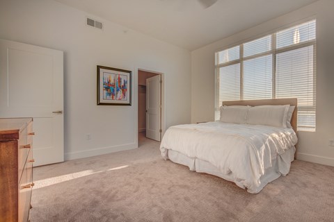 A bedroom with a large bed and a painting on the wall.
