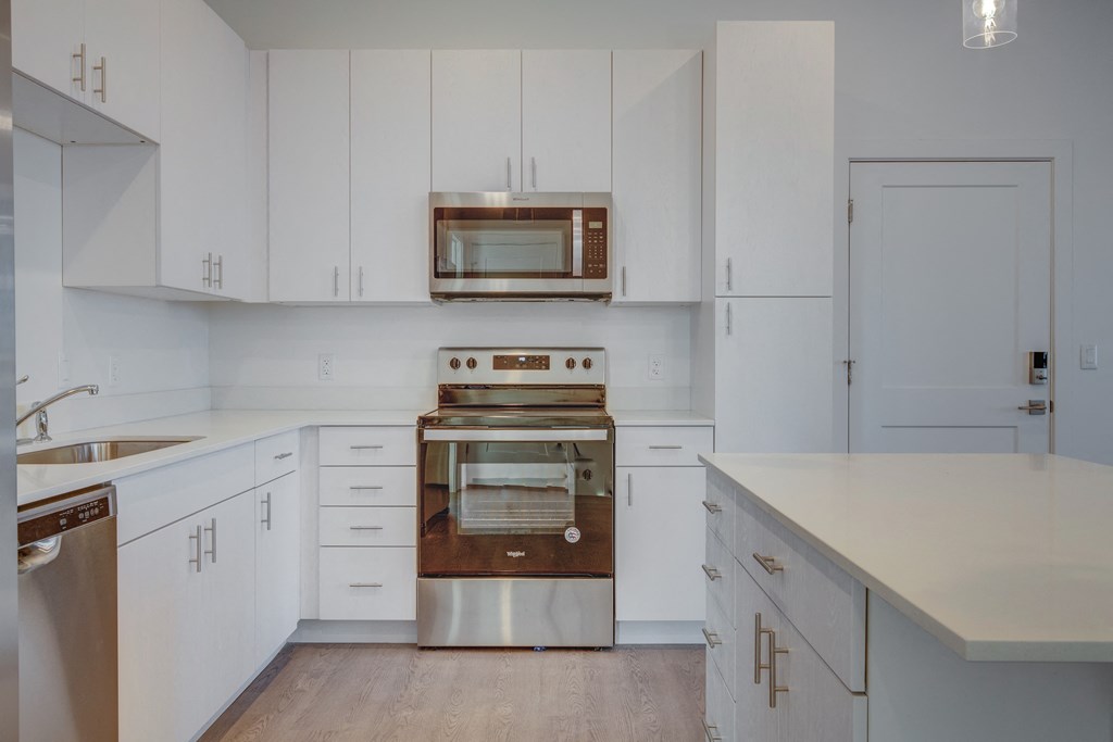 A modern kitchen with white cabinets and stainless steel appliances.