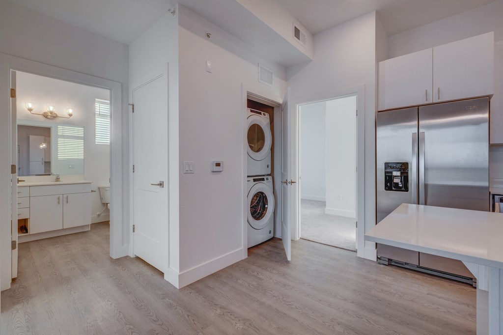 A modern kitchen with white cabinets and a wooden floor.