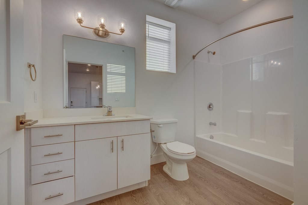A white bathroom with a toilet, sink, and mirror.