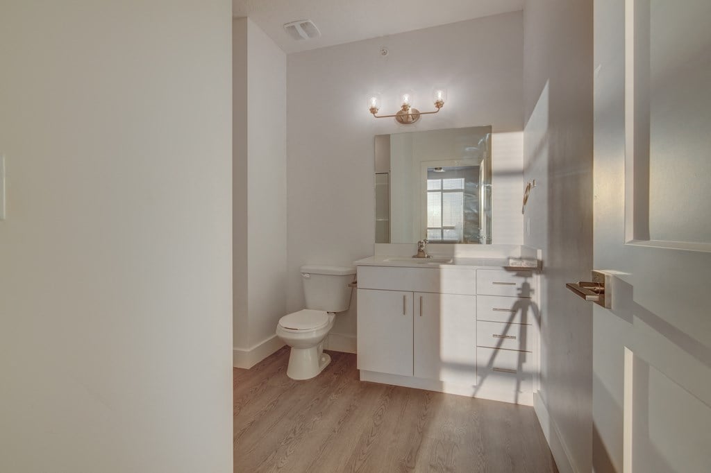 A white bathroom with a toilet, sink, and mirror.