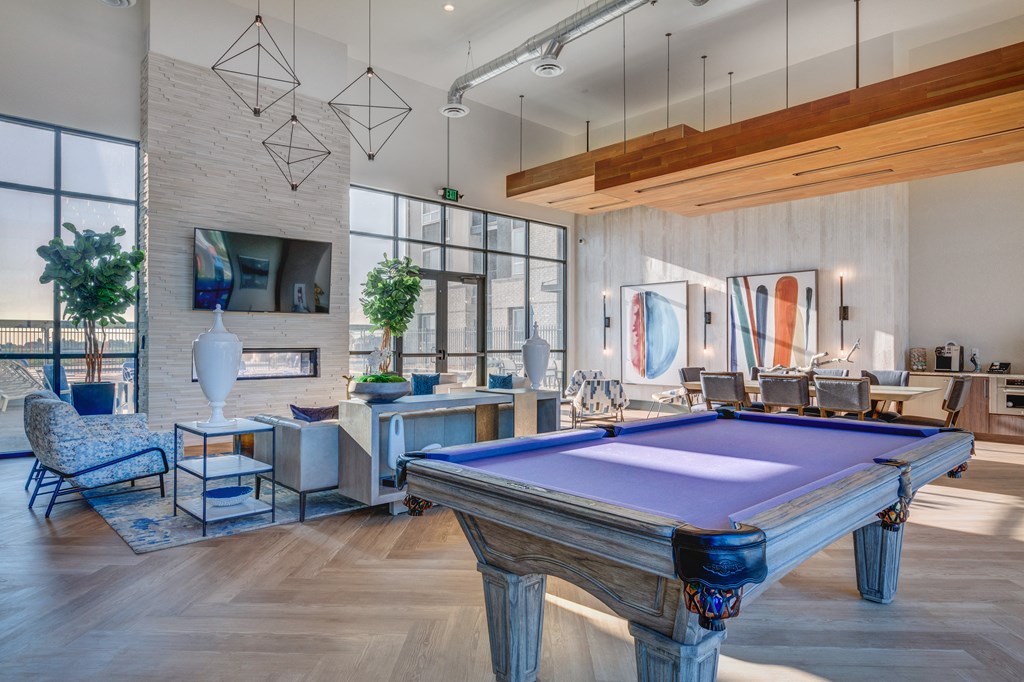 A pool table is in the middle of a room with a TV and a chair.