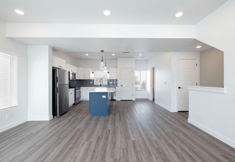 an open kitchen and living room with white walls and wood floors
