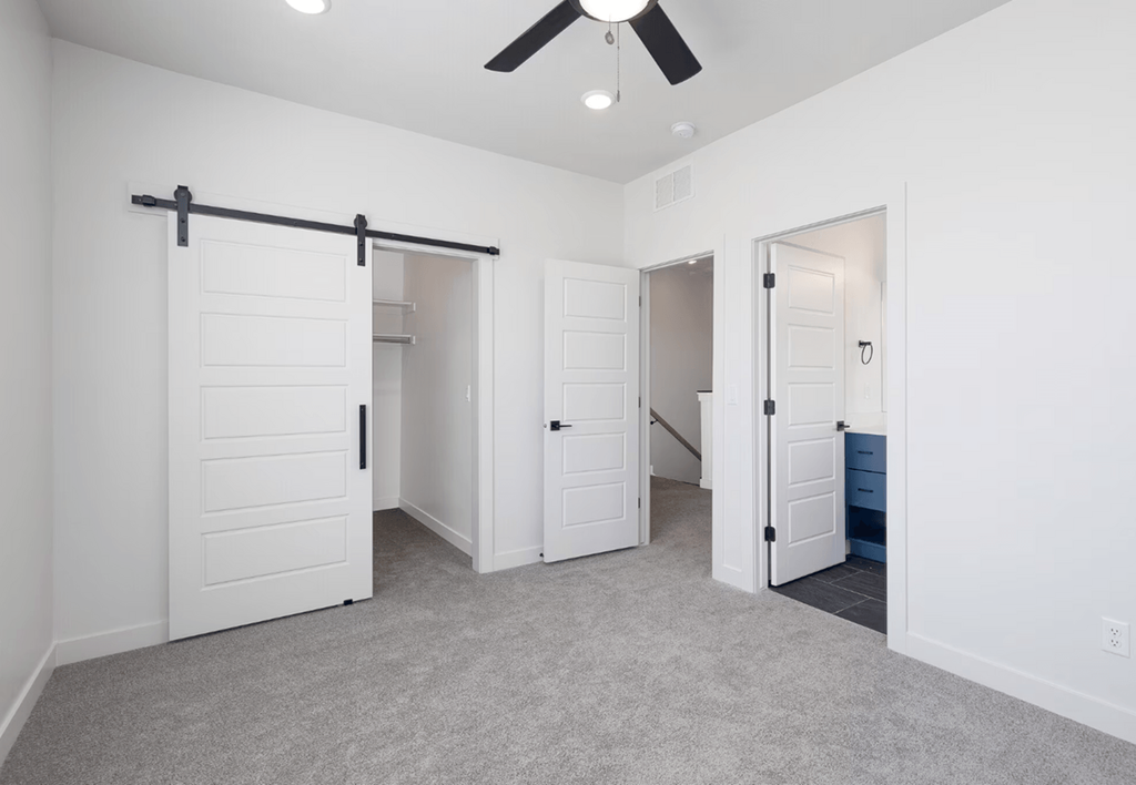 a bedroom with white closets and a ceiling fan