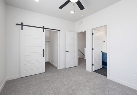 a bedroom with white closets and a ceiling fan