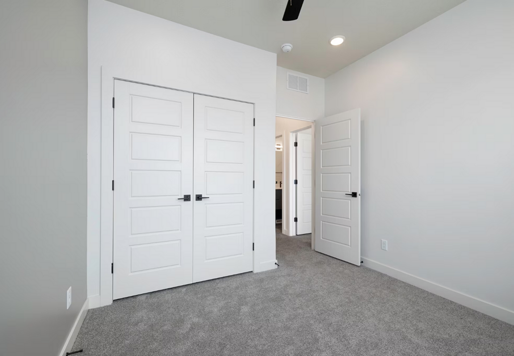 an empty bedroom with two closets and two doors