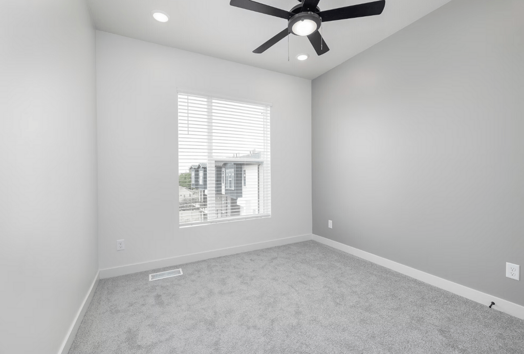 an empty room with a ceiling fan and a window