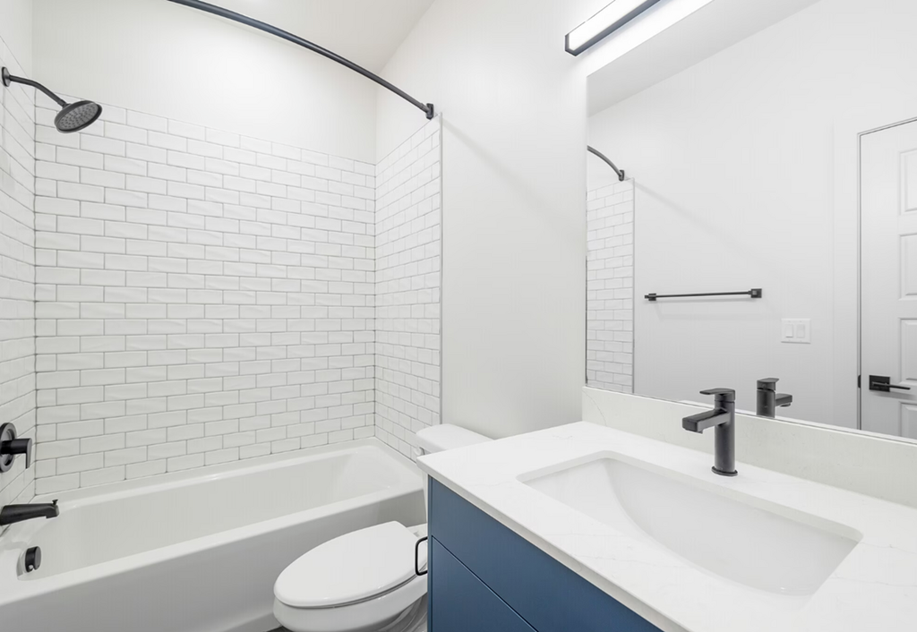 a bathroom with white tiles and a sink and a toilet