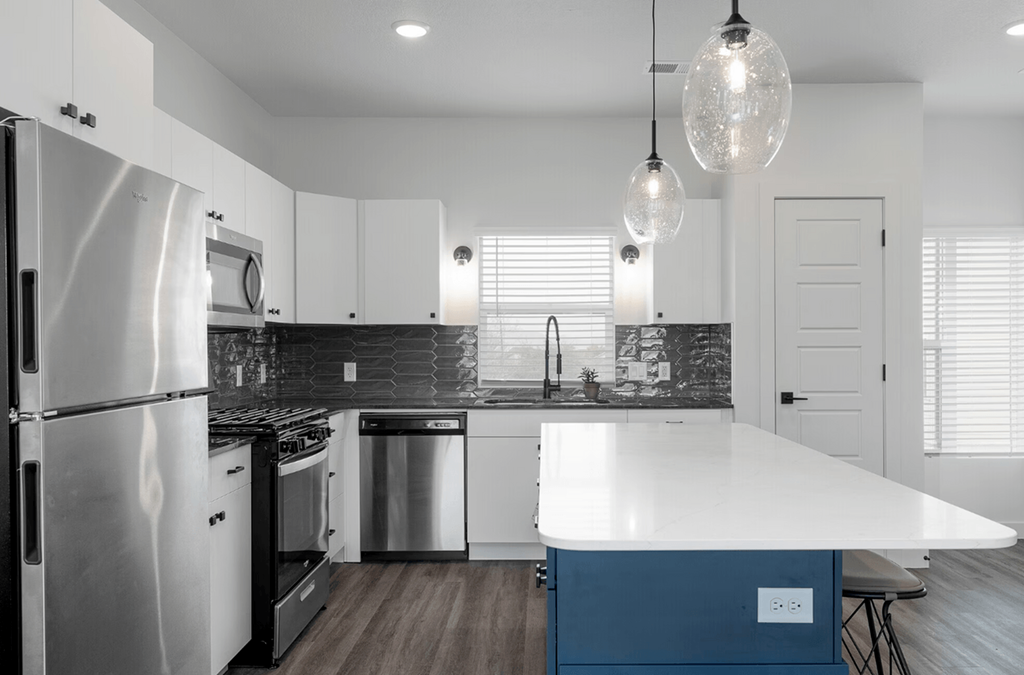 a white kitchen with stainless steel appliances and a blue island