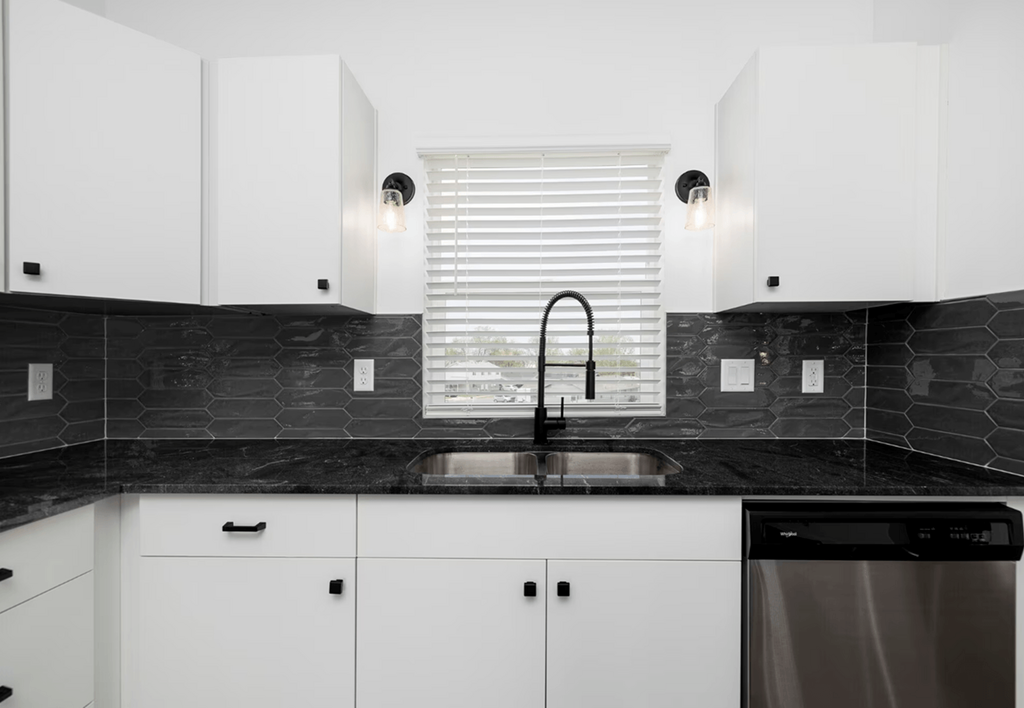 a black and white kitchen with white cabinets and a sink