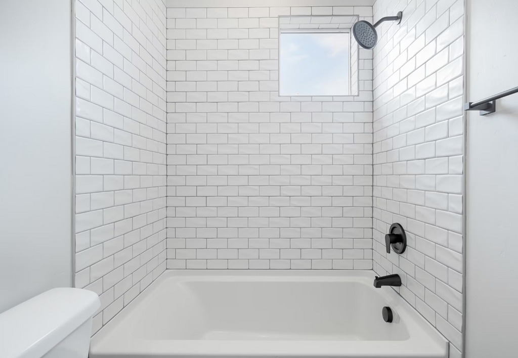 a white bathroom with white tiled walls and a white tub