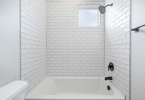 a white bathroom with white tiled walls and a white tub