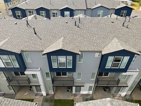 A row of houses with grey roofs and dark blue walls.