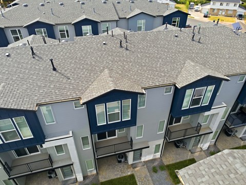 Apartment complex with grey roofs and multiple balconies.