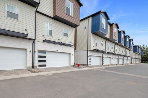 a row of houses with white garage doors and a red fire hydrant