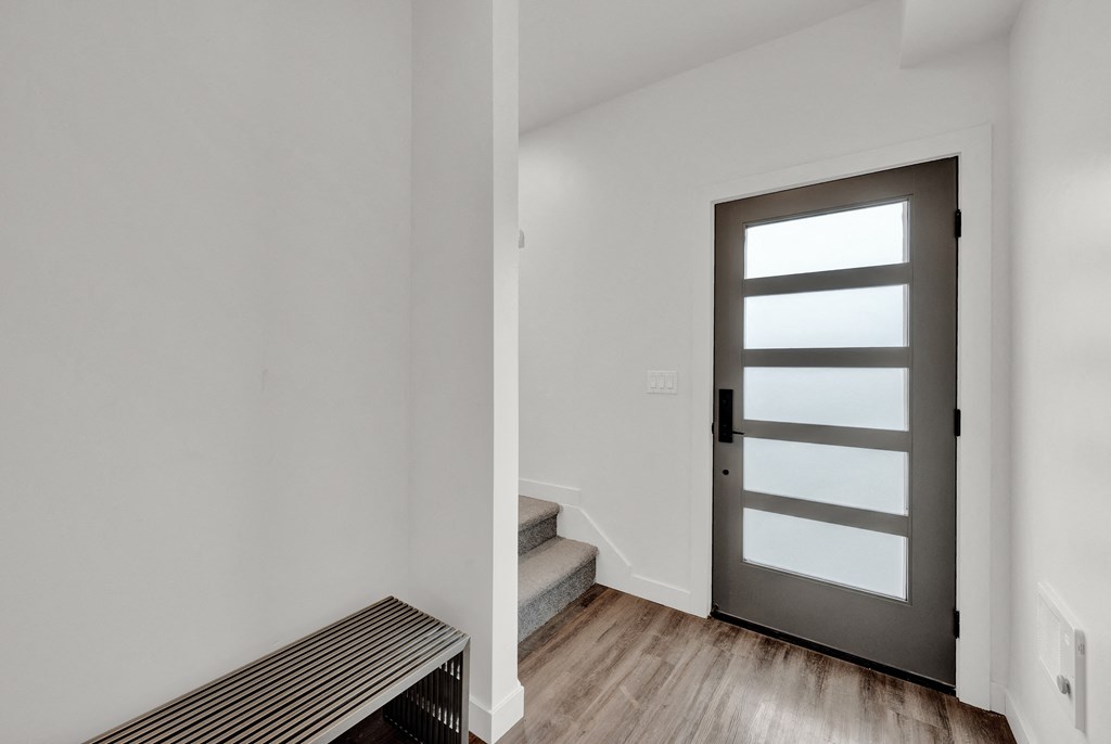 an empty room with white walls and a door with a window and stairs