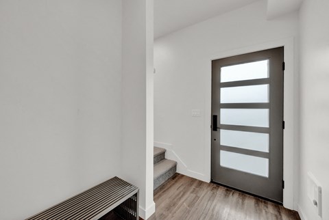 an empty room with white walls and a door with a window and stairs
